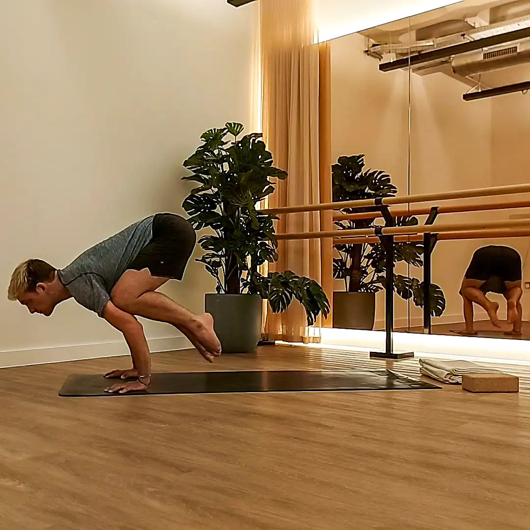 Man in Crow Yoga pose.